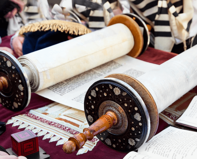A torah scroll is shown on top of the table.