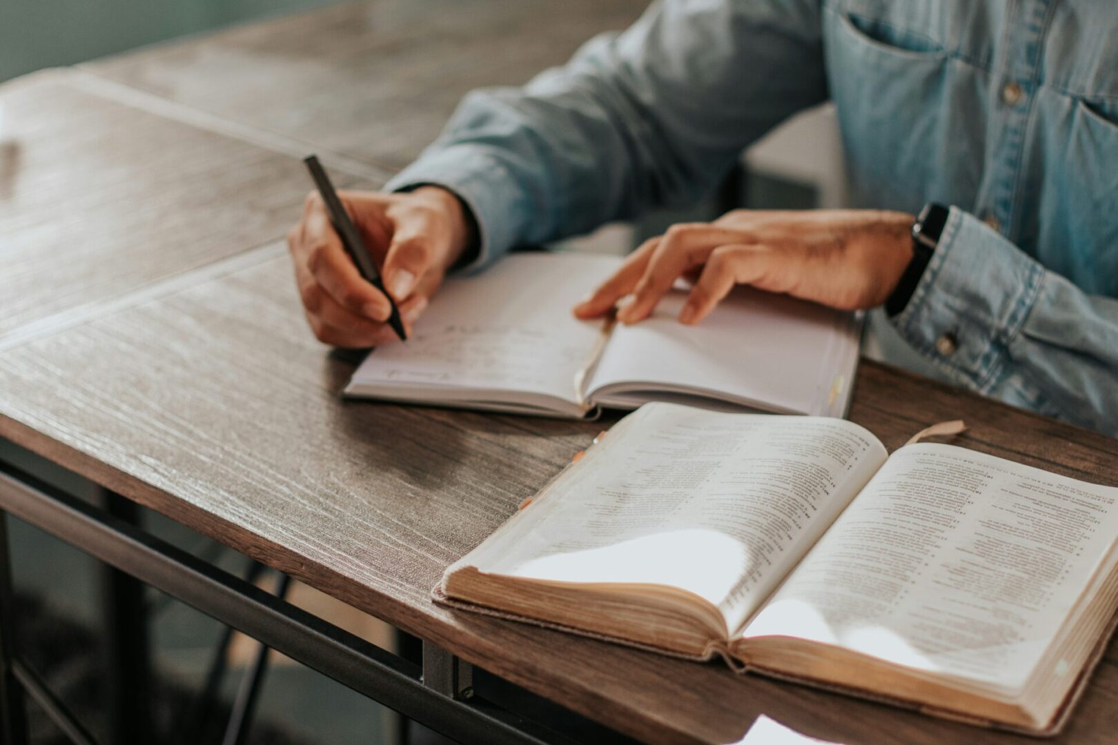 A person writing on some paper while sitting at a table