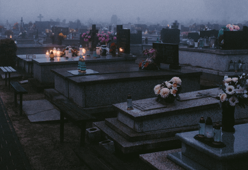 A cemetery with many tombstones and candles lit.