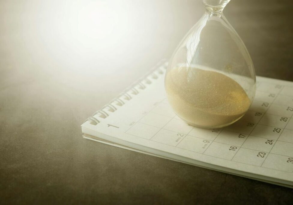 Sand timer sitting on top of a calendar