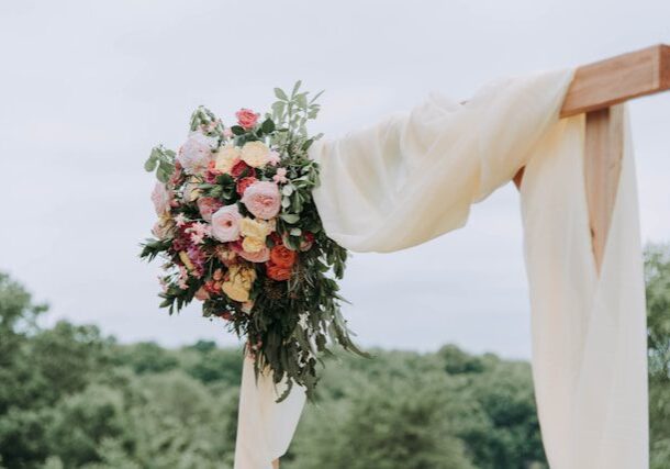 A bouquet of flowers is hanging from the side of a white curtain.