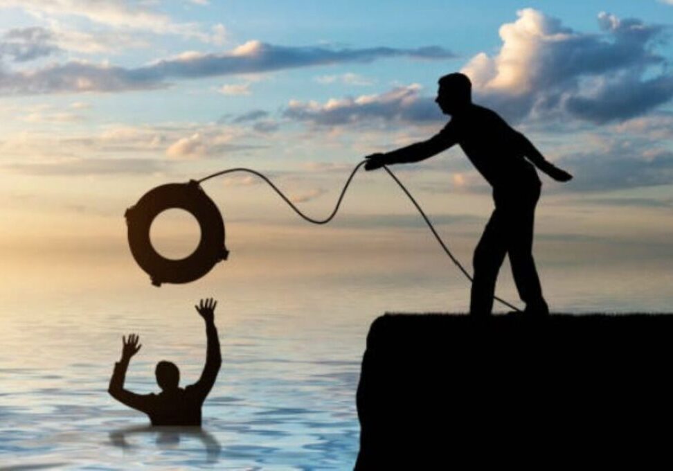 Man on rock outcropping throwing a drowning man a life preserver